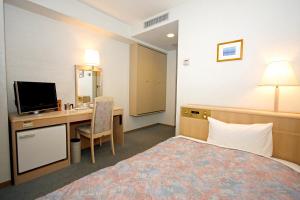 a hotel room with a bed and a desk and a television at Hotel Central Sendai in Sendai