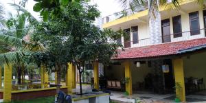 a building with yellow columns and trees in front of it at Holiyday in VGF Farm House in Dānishpet