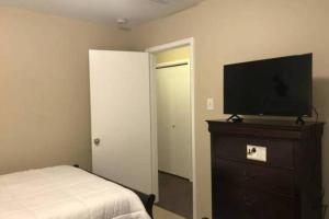 1 dormitorio con cama y vestidor con TV de pantalla plana. en Spacious 3 bed/ 2 bathroom House in Conroe, TX, en Conroe