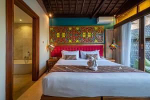 a cat sitting on a bed in a bedroom at Menzel Ubud in Ubud