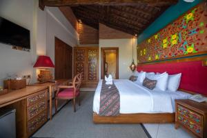a bedroom with a large white bed and a desk at Menzel Ubud in Ubud