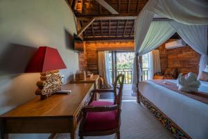 a bedroom with a desk and a bed and a bed and a table at Menzel Ubud in Ubud