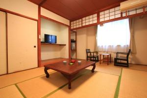 uma sala de estar com uma mesa e cadeiras e uma janela em Banshoukaku em Tsushima