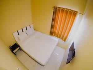 um pequeno quarto com uma cama branca e uma janela em City Residence Kutai 32 em Surabaya