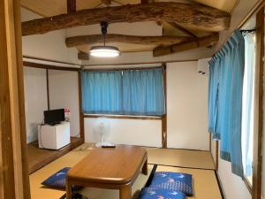 a living room with a wooden table and blue curtains at 民泊はのこの庭 in Kokuryō