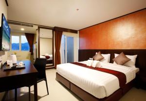 1 dormitorio con cama, escritorio y ordenador en Orchid Resortel, en Patong Beach