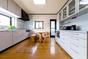 iine في فوجيكاواجوتشيكو: مطبخ فيه دواليب بيضاء وطاولة فيه