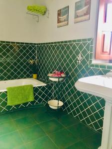 baño de azulejos verdes con bañera y lavamanos en Casa Mayor, en Gordexola