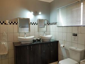 een badkamer met 2 wastafels en een toilet bij Graceland Guesthouse in Potchefstroom