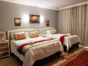 a bedroom with two beds with white sheets at Graceland Guesthouse in Potchefstroom