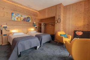 Cette chambre d'hôtel comprend deux lits et une chaise jaune. dans l'établissement Hôtel Astérides Sacca, à Cauterets