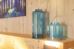 três vasos de vidro azul sentados numa prateleira de madeira em Hôtel Astérides Sacca em Cauterets