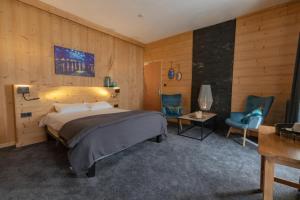 a bedroom with a bed and two blue chairs at Hôtel Astérides Sacca in Cauterets