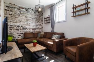 sala de estar con muebles de cuero y pared de ladrillo en Design Industriel avec Terrasse Privative, en Gignac-la-Nerthe