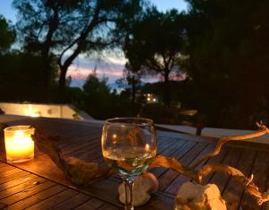 una copa de vino sentada en una mesa de madera con una vela en Villa Pilion en Kolios