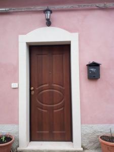 una puerta de madera en un edificio rosa con plantas en Casa Vacanze Il Paese Dipinto en Montegiordano