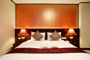 a bedroom with a large white bed with two lamps at Orchid Resortel in Patong Beach