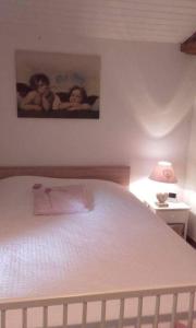 - une chambre dotée d'un lit blanc avec une photo sur le mur dans l'établissement Les Demeures de la Laigne, à Allas-Bocage