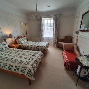 a bedroom with two beds and a couch and a chair at Moraybank Bed & Breakfast in Elgin