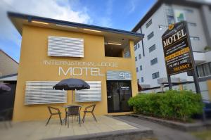 una cafetería con sillas y una sombrilla frente a un hotel en International Lodge Motel, en Mackay