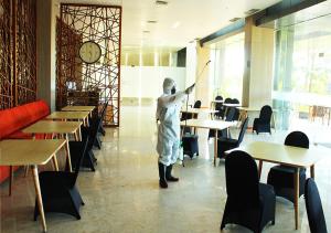 a person standing in a dining room with a wand at Gammara Hotel Makassar in Makassar