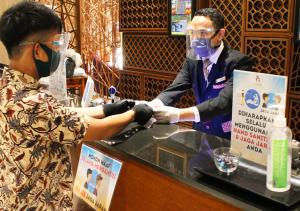 a man wearing a face mask and a woman at a counter at Gammara Hotel Makassar in Makassar