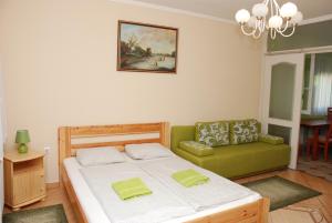 um quarto com uma cama e um sofá verde em Zöldike Vendégház em Kaposvár