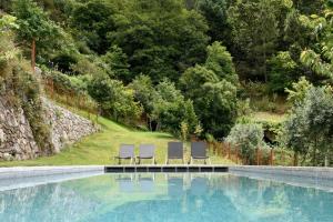 two lounge chairs sitting next to a swimming pool at Casas Da Lapa, Nature & Spa Hotel in Seia