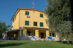 een geel huis met twee blauwe stoelen ervoor bij B&B Roman Country Villa in Zagarolo