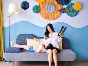 头顿ibis Styles Vung Tau的坐在沙发上的女人,和女孩一起读书 更多37张照片