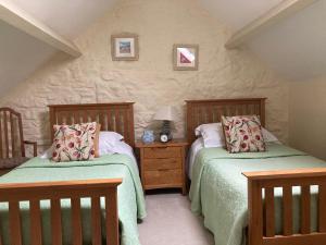 a bedroom with two beds and a table with a lamp at Courtyard Apartment in Shepton Mallet