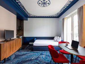 Aparthotel Adagio Paris Haussmann Champs Elysées في باريس: غرفة فندقية بسرير وطاولة وكراسي