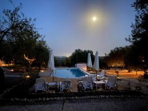 a pool with chairs and umbrellas at night at Mennuli&Alivi - Organic Farm in Noto