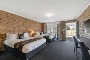Comfort Inn Flinders on Main في بورت بيري: غرفة فندقية بسريرين وجدار من الطوب