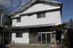 una casa blanca con una puerta delante en Hase Ryokan, en Shingu
