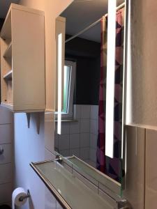 specchio in bagno con lavandino e finestra di Große Ferienwohnung an der Rheinpromenade three a Duisburg