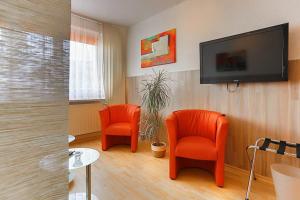 a room with two orange chairs and a flat screen tv at H&H Apartment im Herzen der Stadt Nr 29-Henning mit Balkon in Greifswald