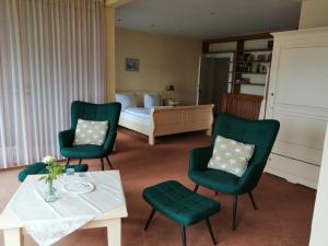 a room with a bed and two green chairs and a table at Hotel Fährhaus Niederkleveez in Bösdorf