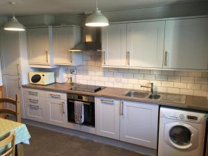 a kitchen with white cabinets and a sink and a dishwasher at George's House - 1 Leacklee in Manish
