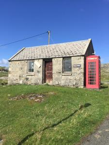 an old stone house with a red phone booth at George's House - 1 Leacklee in Manish