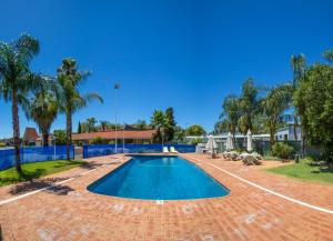 einen Pool in einem Garten mit Palmen in der Unterkunft Hospitality Kalgoorlie, SureStay Collection by Best Western in Kalgoorlie