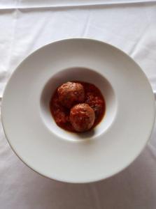 un plato blanco con albóndigas y salsa en una mesa en Hotel Leon D'Oro, en Castelfrentano