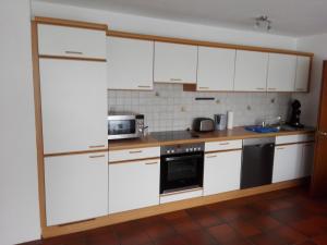 a kitchen with white cabinets and a stove top oven at Haus Annette in Weiswell