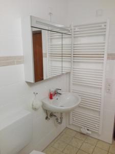 ein weißes Badezimmer mit einem Waschbecken und einem Spiegel in der Unterkunft Haus Annette in Weiswell