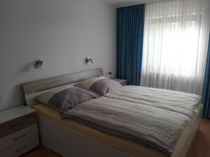 a bedroom with a bed and a window with blue curtains at Haus Annette in Weisweil