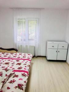 a bedroom with a bed and a dresser and a window at Casa Craciun Ciocanesti in Ciocăneşti