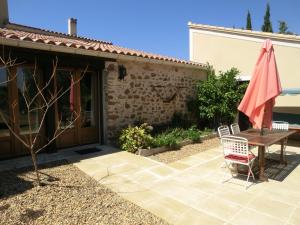 a patio with a table and an umbrella at Gite Charlrose at La Platriere in Cazedarnes
