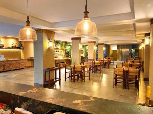 Natal Dunnas Hotel في ناتال: مطعم بطاولات خشبية وكراسي واضاءات