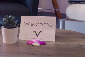 a welcome sign sitting on top of a table with a plant at VIVA Hostel in Chur