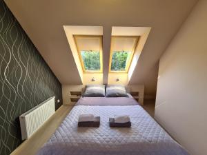a attic bedroom with two beds and two windows at Lux Apartment Duplex in Polanica-Zdrój